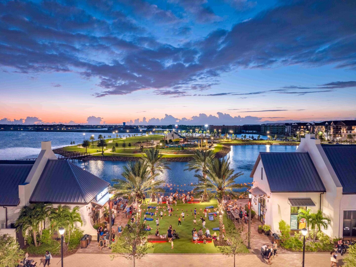 People gather at a waterfront park at dusk.